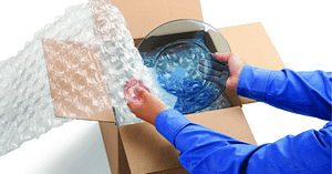 Man, in a blue shirt opening up a box filled with bull wrap and a clear plate