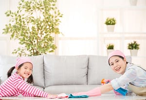 Asian mother and daughter wearing a pink cap wiping a table