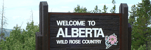 Wooden Alberta tourism logo sign that displays Welcome to Alberta Wild Rose Country